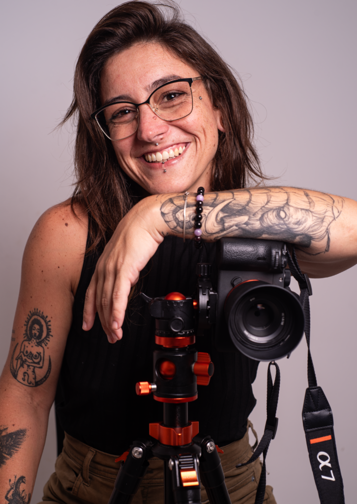 Natália Rabelo, fotógrafa gastronômica e estrategista digital, sorrindo com a câmera no tripé